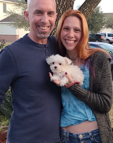man and woman holding a MalShi puppy