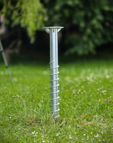 Durable galvanized steel ground screw anchor for secure garden installations in a green lawn.