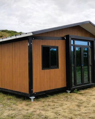 Modern prefabricated modular cabin with wood slat siding and black window frames in a rural landscape.