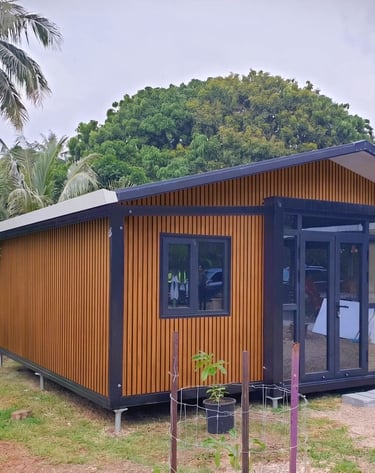 Chalet modulaire moderne avec bardage bois et portes vitrées dans un décor tropical.