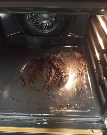 “Restos de comida quemada y manchas de grasa en el fondo de un horno eléctrico sucio