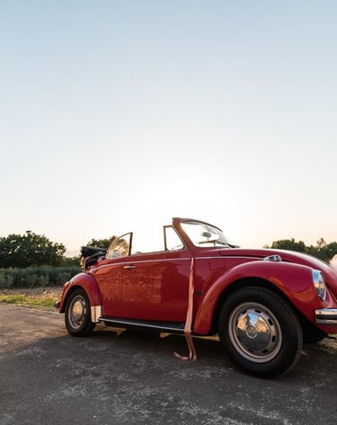 Maggiolone rosso d'epoca allestito per un matrimonio in campagna.