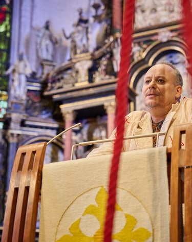 Ein Schauspieler am Rednerpult einer Kirche. Im Vordergrund ein rotes Seil.