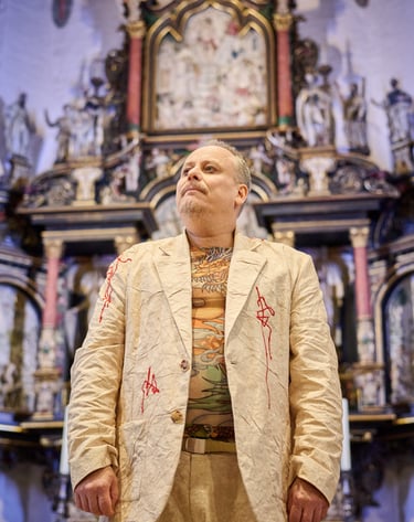 Ein Mann in hellem Anzug steht vor einem Kirchenaltar und schaut entschlossen.
