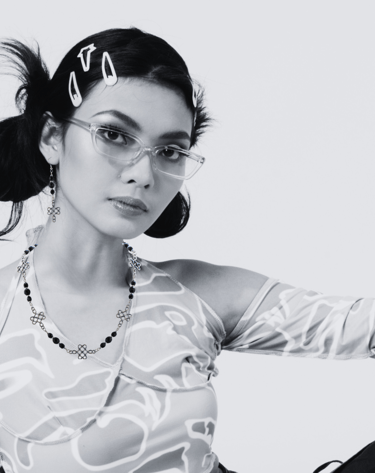 Stylish woman wearing glasses, hair clips, a patterned halter top and necklace and earrings set