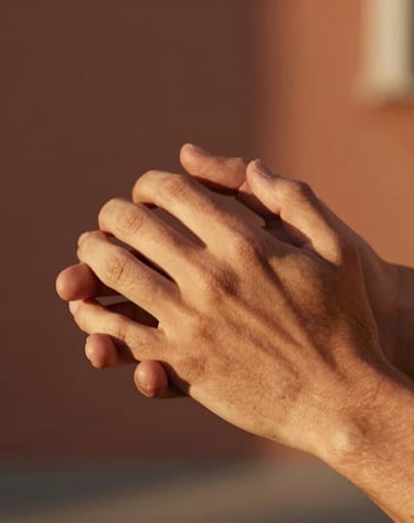 A close-up candid photograph of hands gently holding each other. Set in Southern Europe during late afternoon, with warm terracotta tones in the background, cinematic soft light casting long shadows, highly detailed skin textures, lifestyle photography style.