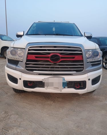 Front view of a white modified RAM pickup truck with a custom red and chrome grille parked on sand.