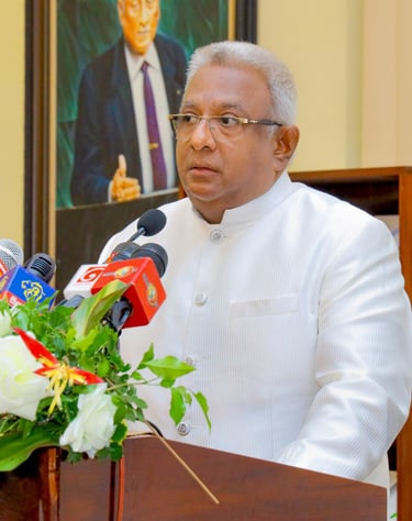 a man in a white suit and glasses speaking into microphones