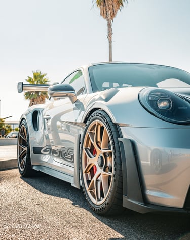 a silver sports car parked in front of a palm tree