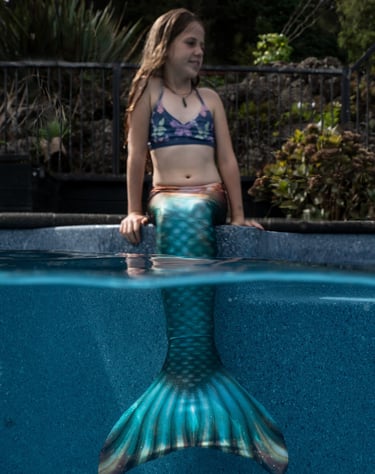 Mermaid sitting in her tail on the pools edge