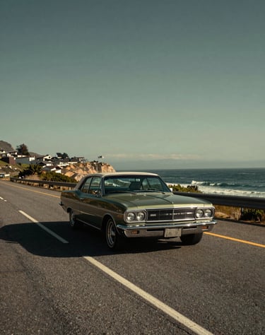 Cinematic travel photography of a vintage car driving along a coastal North American / US highway, artistic perspective, warm afternoon sun, Dark Charcoal and Olive Green tones.
