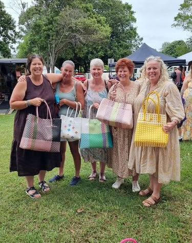 a group of women standing in a field with bags