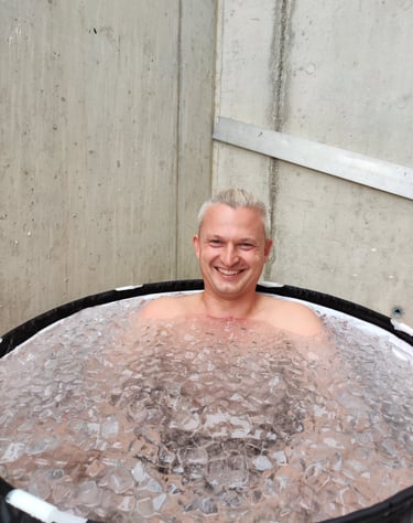 Mann der lachend und fröhlich im Eisbad sitzt