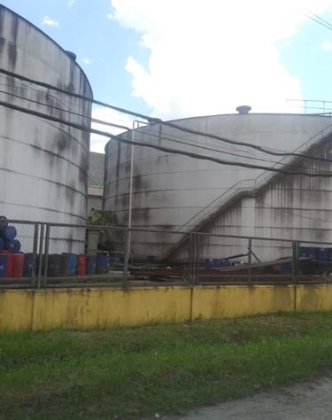 Industrial storage tanks and chemical barrels at an oil and gas refinery facility.