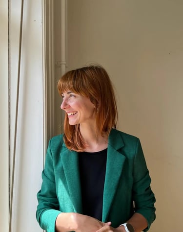 A smiling woman in a green blazer looking to the side, representing a client after an RTT session