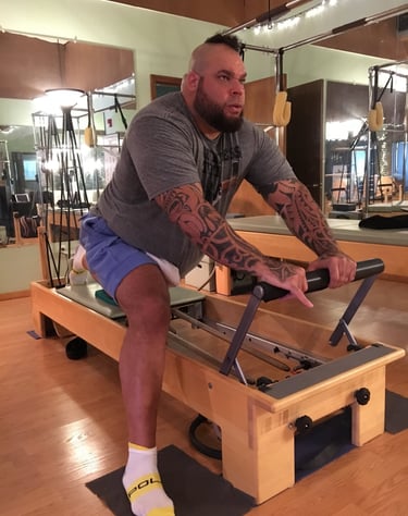 one man on a pilates reformer doing a stretch