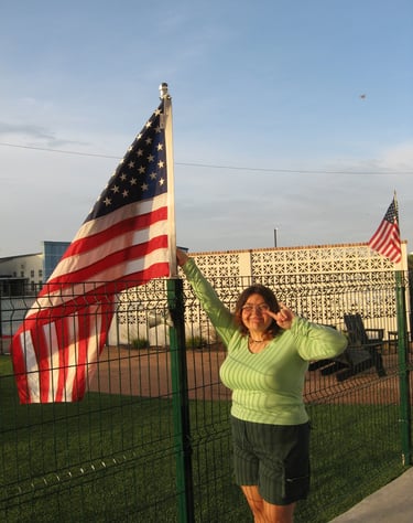 A girl next to a USA flag taking a picture 