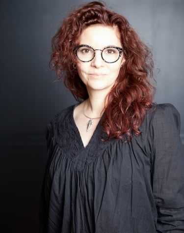Marion Herlédan is a woman with red hair and glasses on a black background she is a food photographe