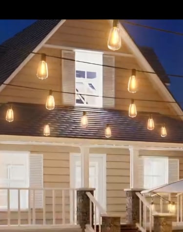 Warm outdoor string lights hanging over a cozy house porch and patio at dusk for backyard lighting decor.