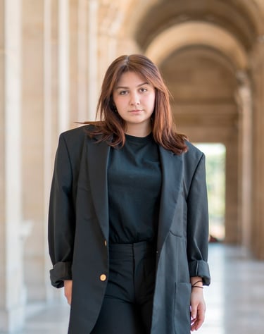 Portrait d’une modèle dans une galerie parisienne, habillée en noir, dans un décor élégant aux colonnes et arches en perspect
