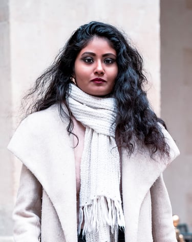 Portrait d’une modèle en manteau d’hiver clair et écharpe, posant avec assurance devant un mur beige.