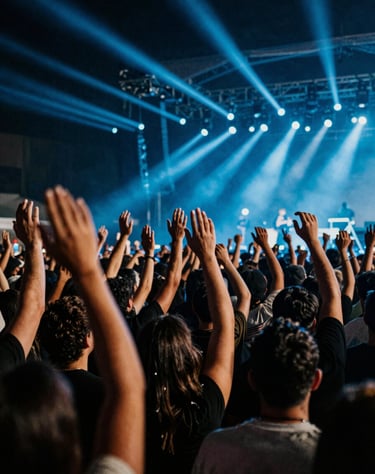 Wide shot of a crowd at a concert in Bogotá, hands raised against a background of dark shadows and electric blue stage lights. High energy, cinematic.