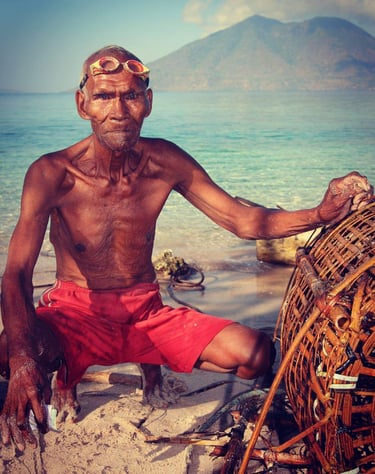 an older alor man with freediving goggles and his fishing cage made of bamboo