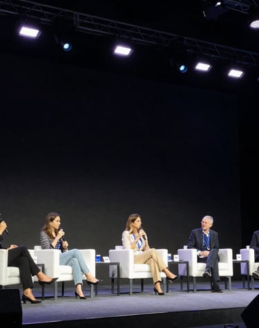 A wide angle photograph of a keynote panel at a high-end technology conference in Latin America, with a female expert answering questions under pristine stage lights.