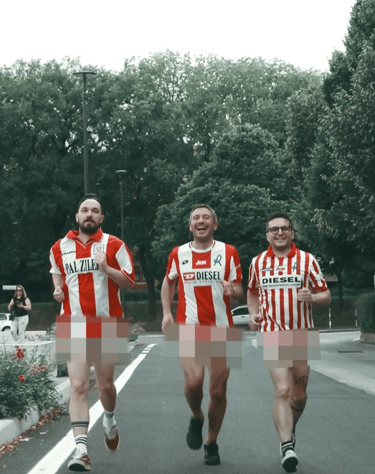 Three men jogging outdoors wearing red and white striped soccer jerseys for a charity run.