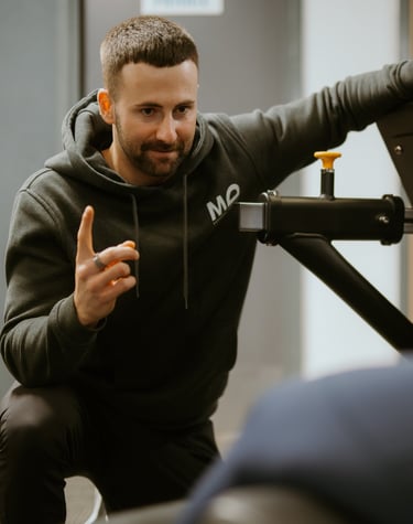 Personal trainer in hoodie coaching client on gym equipment in Leamington Spa fitness centre, focused on technique and su