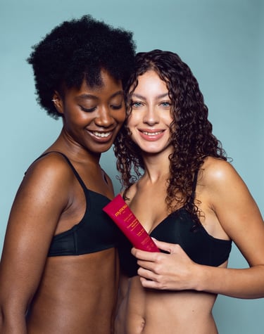 Deux jeunes femmes posant sur un fond bleu avec un gommage rose dans la main
