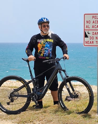 a man standing next to a sign at El Faro,  Cabo Rojo