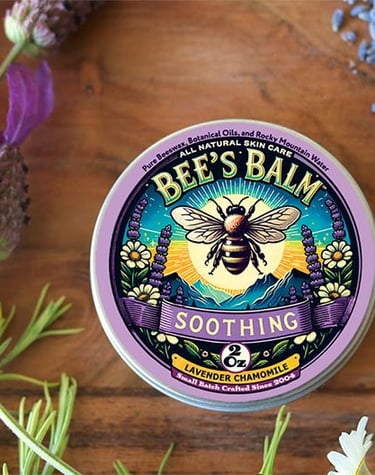 Tin of Soothing Bee's Balm surrounded by Lavender Sprays and buds & Chamomile flowers and 