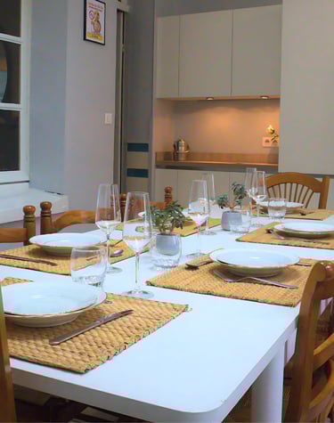 Salle à manger avec grande table dressée et cuisine équipée pour équipes en mission.