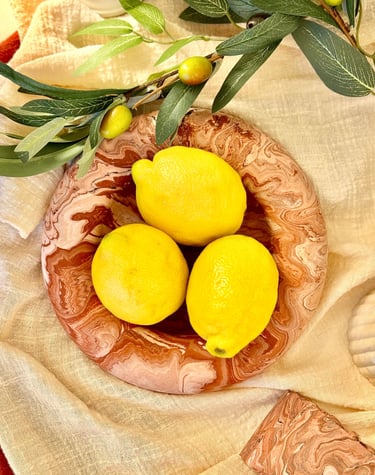 3 citrons jaunes posés sur une assiette en marbre terracotta