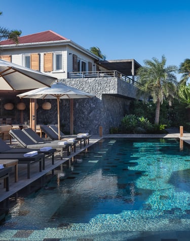 a pool with lounge chairs and umbrellas at villa noah st barth