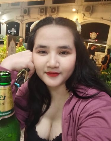 Lady seated with fisted hand on cheek with a bottle of beer in front of her