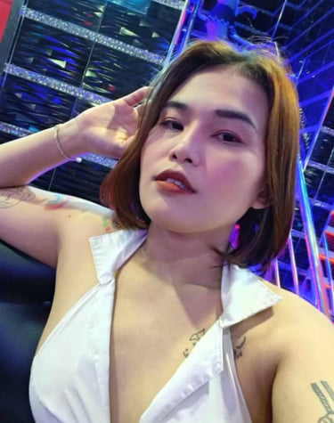 Lady sat on a sofa with on hand on her head and wearing a white sleeveless top 