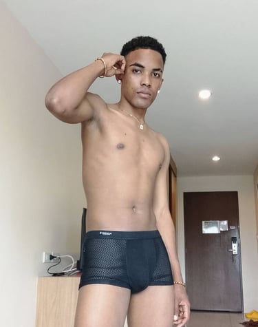 Man standing and wearing black boxer style underwear with his right hand up against his ear