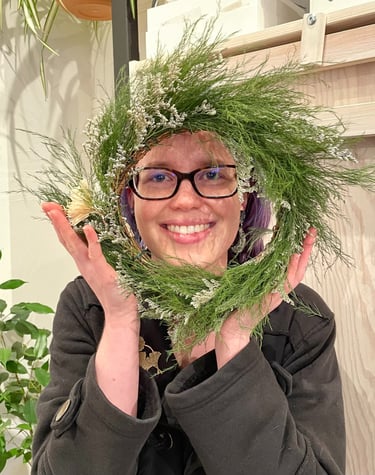 a woman holding a wreath of pine needles