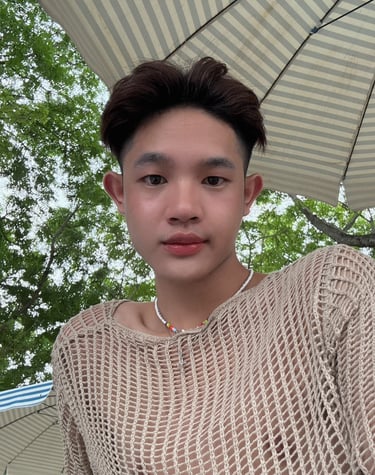 A man wearing a mesh top with large umbrella in the background