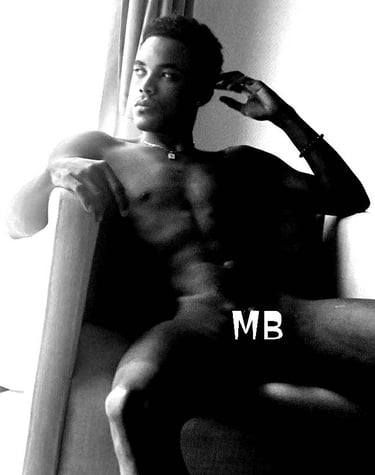 A man sat in the nude on an armchair but with the letters MB covering his private parts