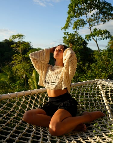 a woman sitting in a hammock during the sunset. the woman is a model