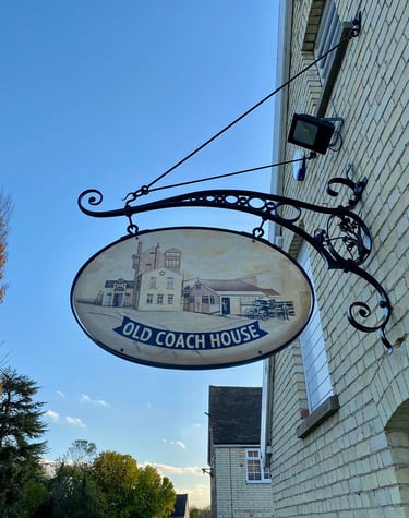 A classic sign indicating the old coach house, affixed to a brick structure, reflecting its historical significance. 