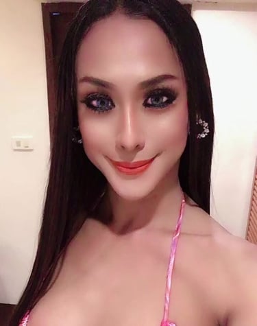 Ladyboy with long black hair wearing a sexy pink and white dress