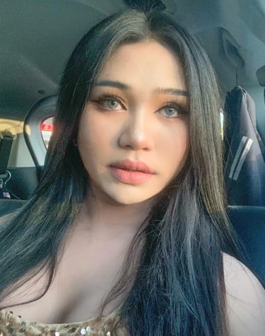 Facial shot of ladyboy looking straight and wearing a low cut gold sequence dress