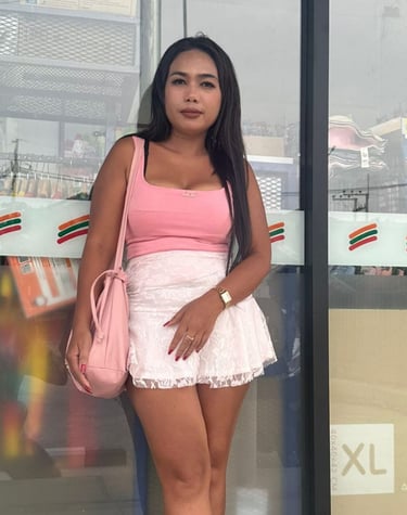 Lady leaning against a shop window wearing short white skirt and sleeveless pink top