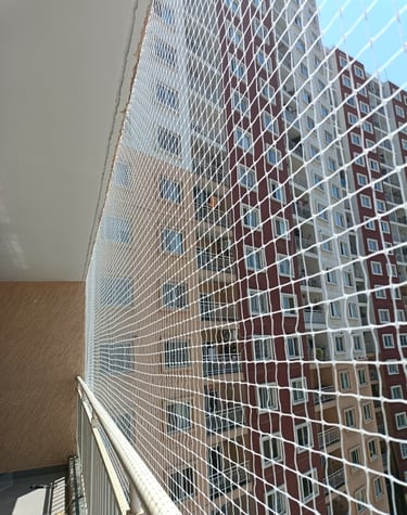 A child playing safely behind a securely fastened balcony safety net.