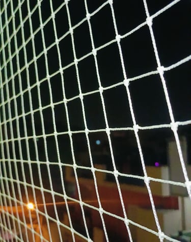 Evening view of a balcony net gently illuminated by warm indoor lights, ensuring safety and peace.