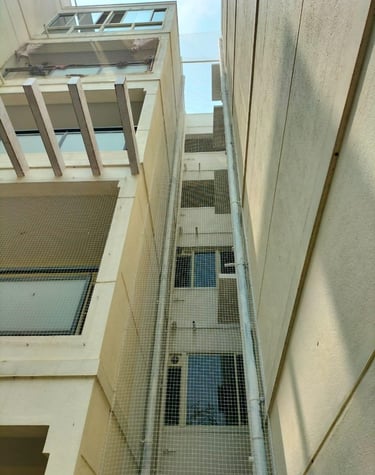 Wide shot of a multi-story building in Whitefield with freshly installed safety nets on all windows.